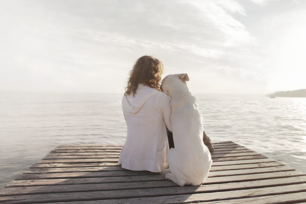 woman sitting on dock with dog