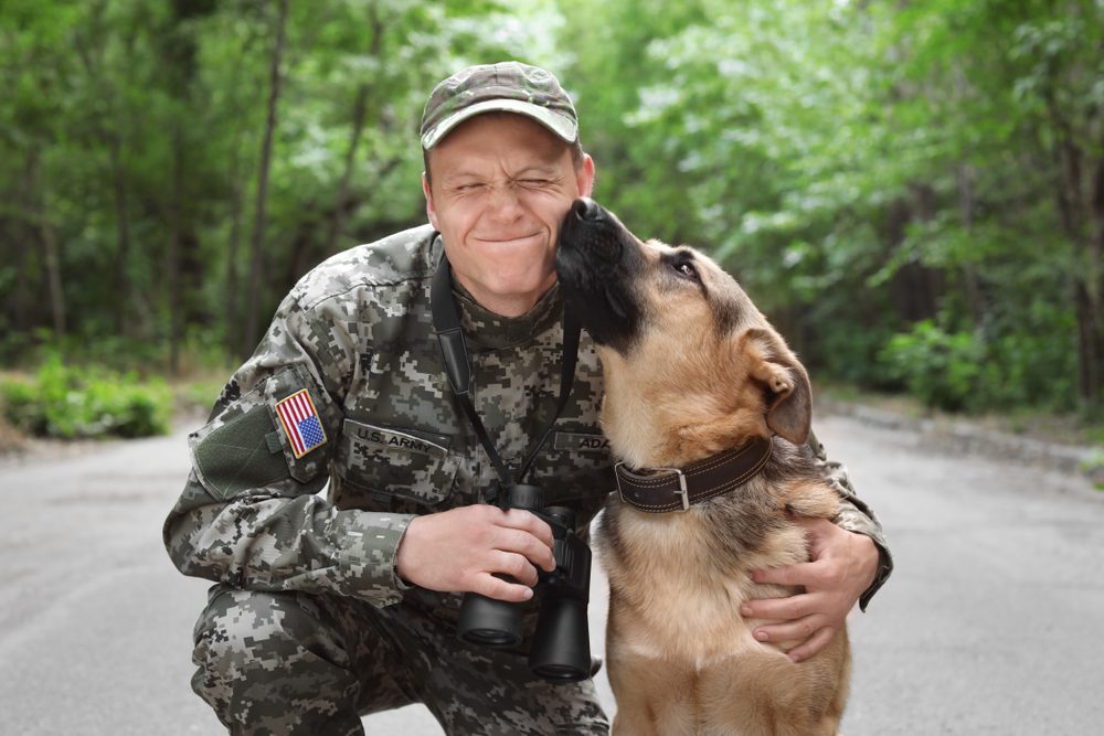 man in military uniform with German Shepherd