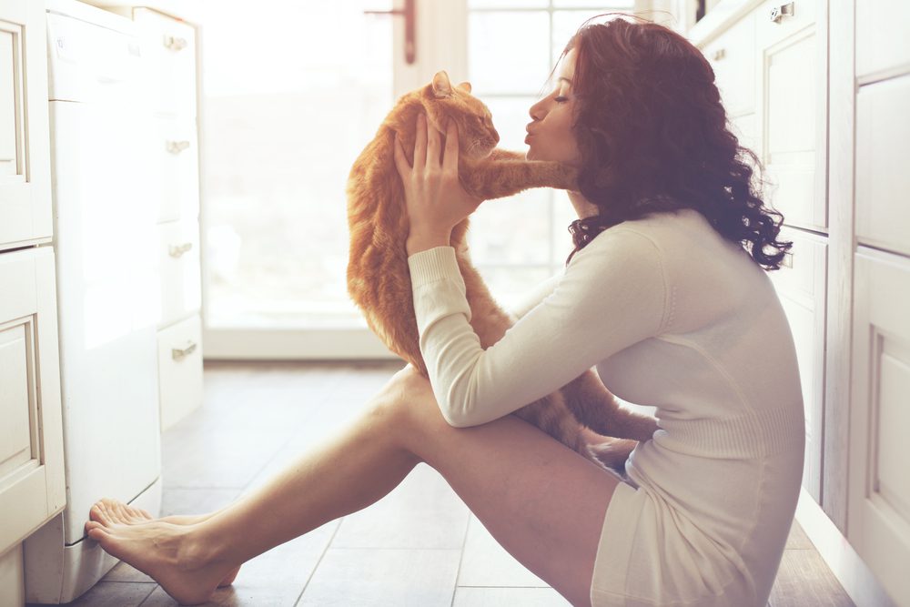 woman holding cat on kitchen floor
