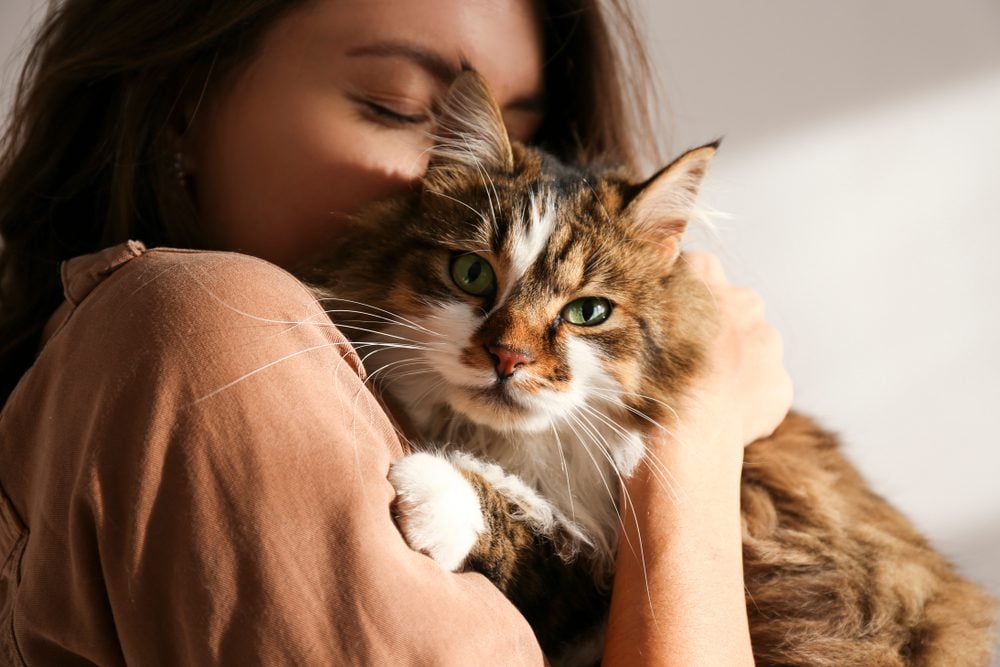 Young woman cuddling cat close